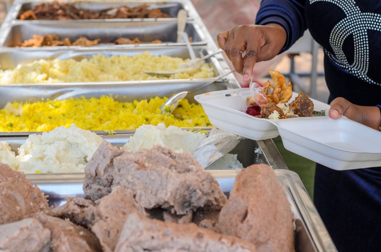 Une personne se sert divers aliments depuis un buffet pour les déposer dans son assiette.