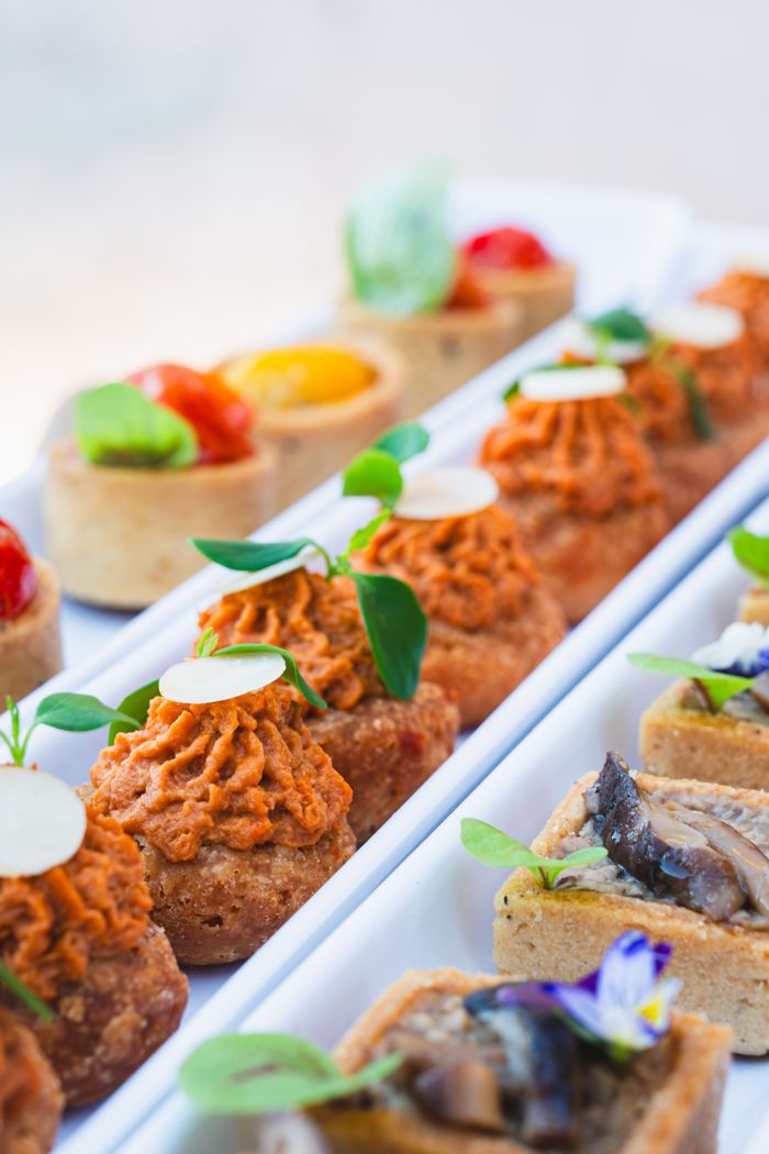 Un assortiment coloré d'amuse-bouches gastronomiques, mettant en vedette des ingrédients éclatants et une présentation élégante sur un plateau blanc.