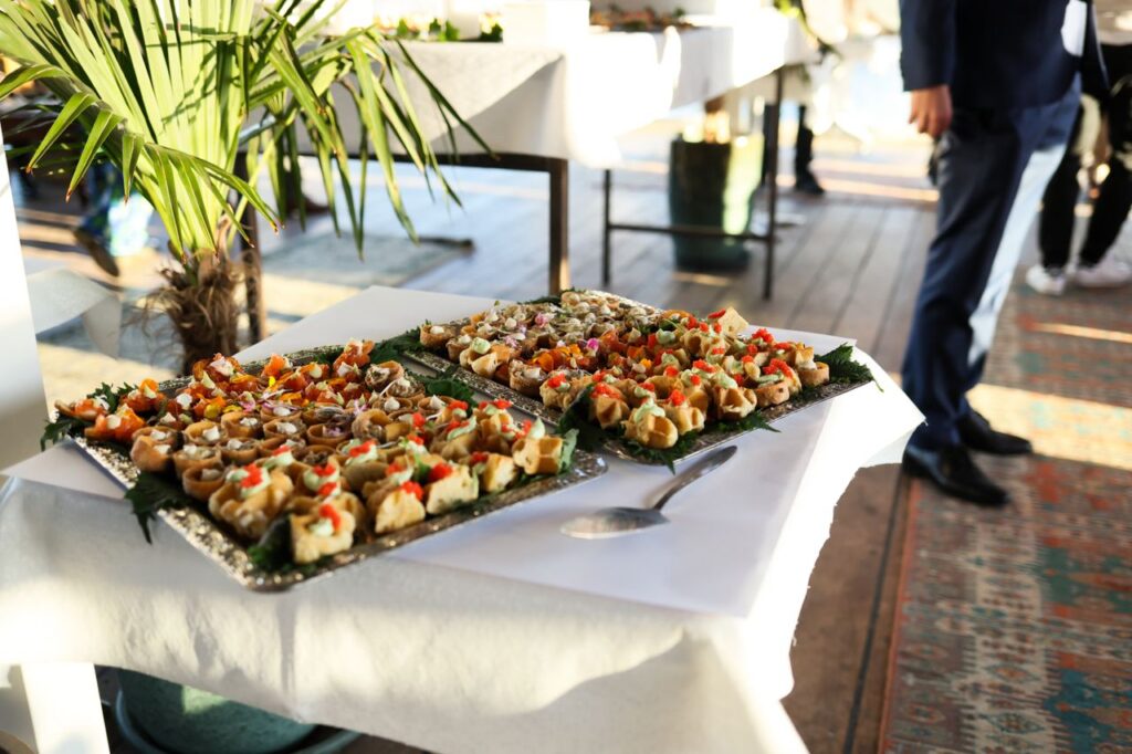 Gourmet appetizers at a stylish indoor event with attendees in formal attire.