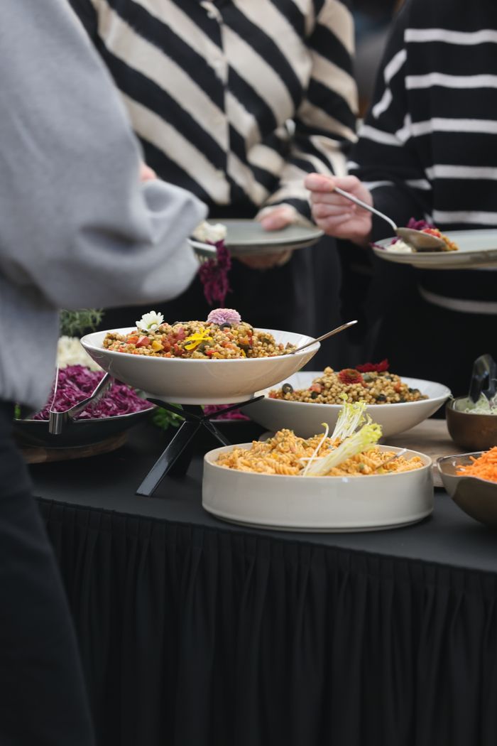 Un assortiment varié de plats colorés sur un buffet lors d'un rassemblement, comprenant des salades et des céréales.