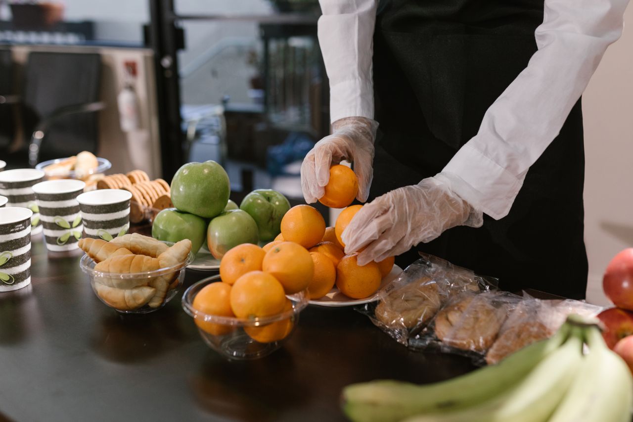 Un traiteur dispose des fruits frais et des en-cas sur une table pour un événement de restauration.